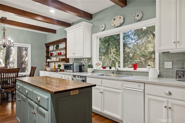 kitchen with white cabinets, appliances with stainless steel finishes, a center island, sink, and backsplash