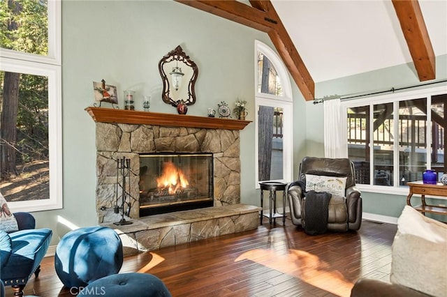 sitting room with beam ceiling, wood-type flooring, a stone fireplace, and high vaulted ceiling