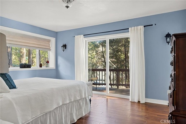 bedroom with access to exterior, multiple windows, and dark hardwood / wood-style floors