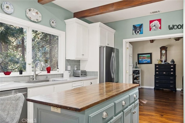 kitchen featuring butcher block countertops, appliances with stainless steel finishes, beamed ceiling, a center island, and sink