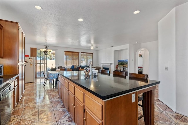 kitchen featuring a kitchen island, a fireplace, a breakfast bar area, dishwashing machine, and hanging light fixtures