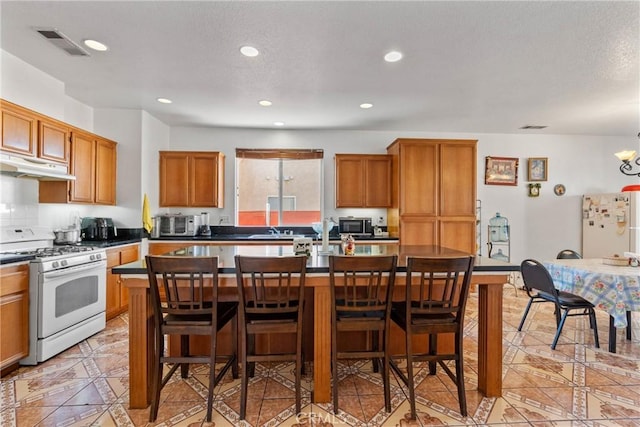 kitchen featuring light tile patterned flooring, white appliances, a kitchen breakfast bar, and a kitchen island