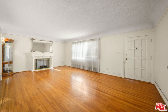 unfurnished living room with hardwood / wood-style flooring and a textured ceiling