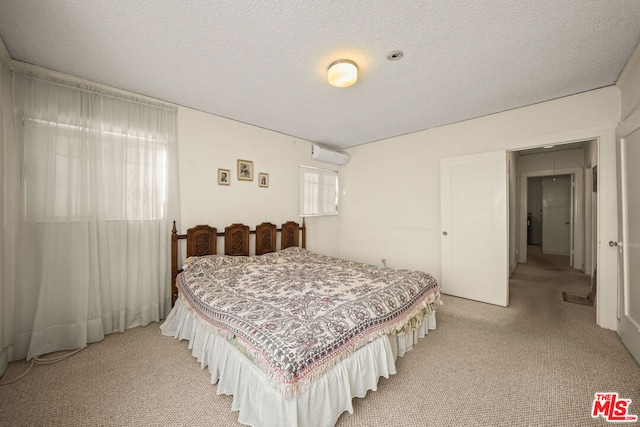 bedroom with a wall mounted air conditioner, light colored carpet, and a textured ceiling