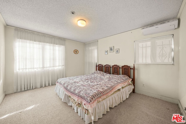 bedroom with an AC wall unit, light colored carpet, and a textured ceiling