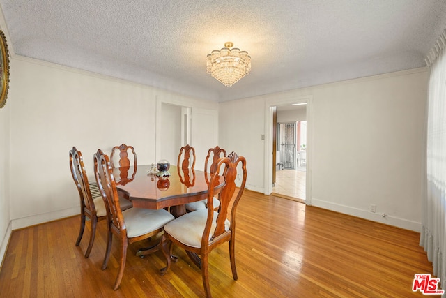 dining space with hardwood / wood-style floors, a notable chandelier, and a textured ceiling