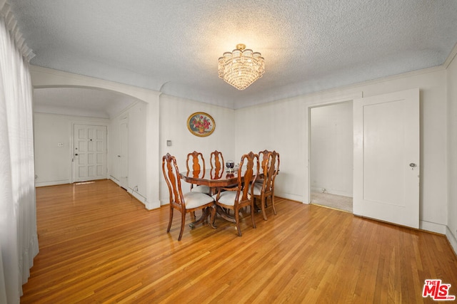 dining area with hardwood / wood-style floors, a chandelier, and a textured ceiling