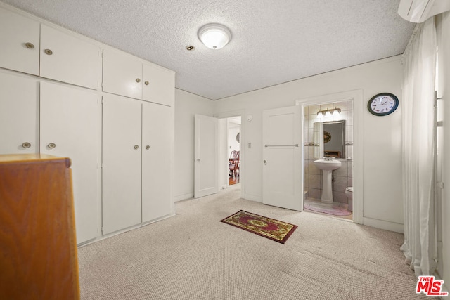 unfurnished bedroom with sink, ensuite bathroom, a textured ceiling, light carpet, and a closet