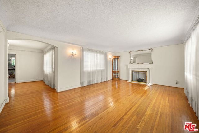 unfurnished living room featuring hardwood / wood-style flooring and a textured ceiling