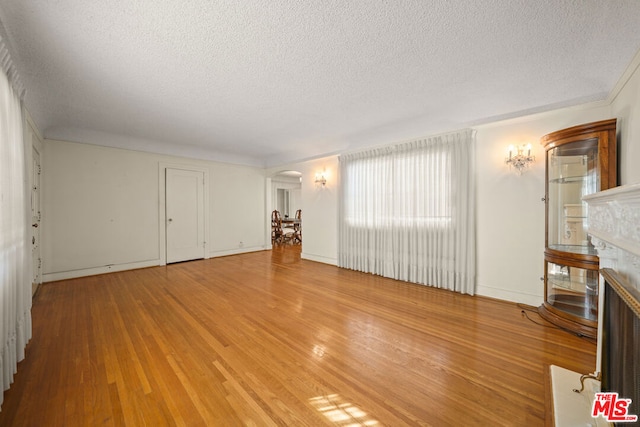 unfurnished living room featuring light hardwood / wood-style floors and a textured ceiling