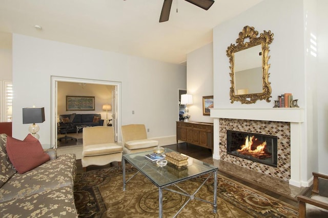 living room featuring a tiled fireplace, hardwood / wood-style floors, and ceiling fan