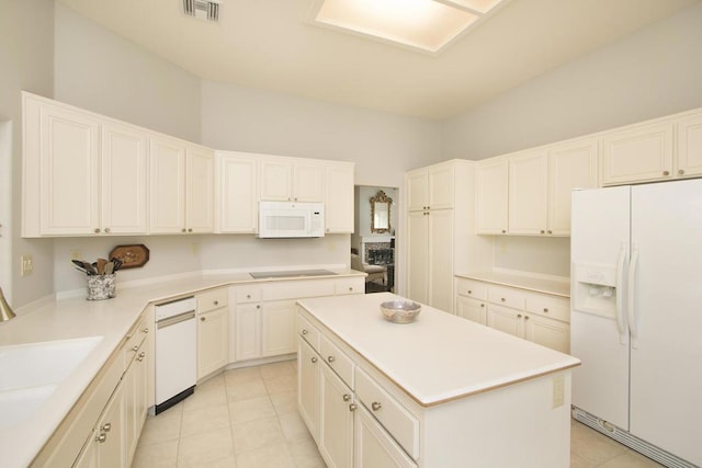 kitchen with sink, white appliances, a center island, white cabinets, and light tile patterned flooring