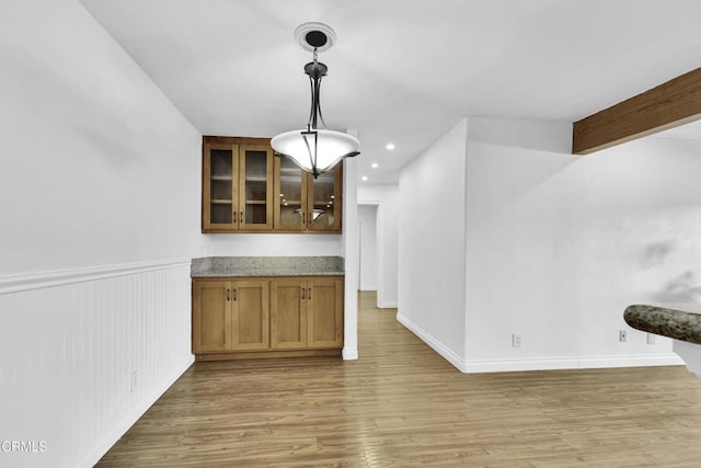 bar featuring light stone counters, hanging light fixtures, light hardwood / wood-style flooring, and beamed ceiling