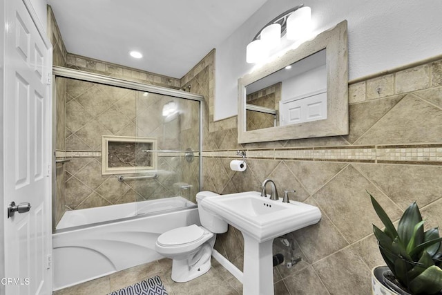 bathroom featuring tile walls, enclosed tub / shower combo, and toilet