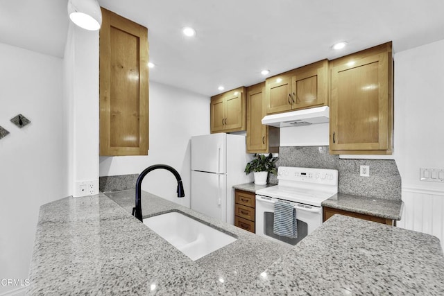 kitchen featuring light stone counters, sink, white appliances, and backsplash