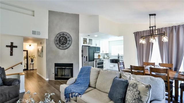 living room featuring sink, hardwood / wood-style floors, a chandelier, and a fireplace