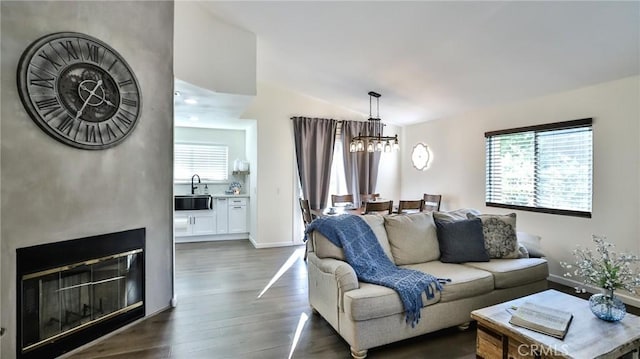 living room with dark hardwood / wood-style flooring, lofted ceiling, a chandelier, and sink