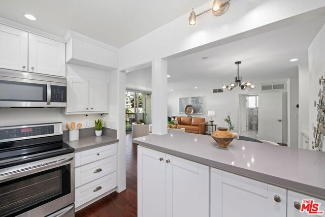 kitchen featuring stainless steel appliances, dark hardwood / wood-style flooring, white cabinetry, and a notable chandelier