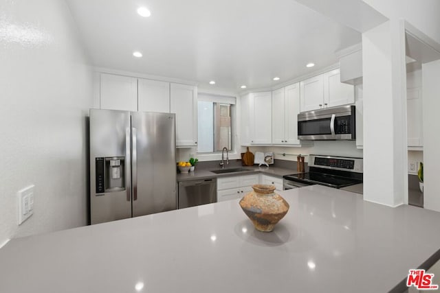 kitchen with white cabinets, kitchen peninsula, appliances with stainless steel finishes, and sink