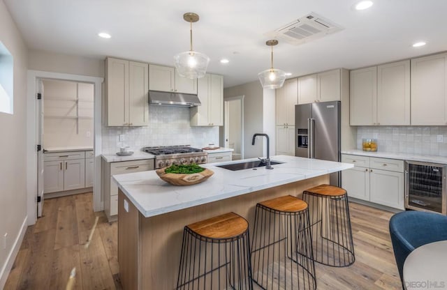 kitchen with sink, high end refrigerator, stove, and a kitchen island with sink