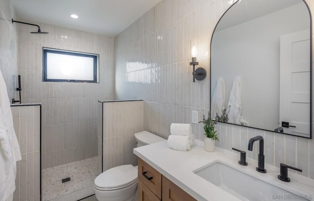 bathroom featuring toilet, vanity, tile walls, decorative backsplash, and a tile shower