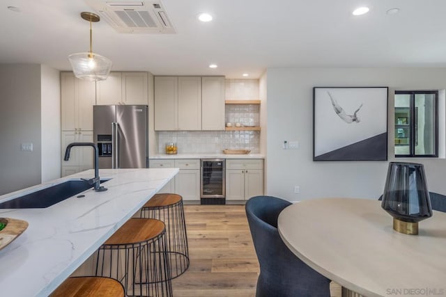 kitchen with wine cooler, decorative backsplash, sink, hanging light fixtures, and high end refrigerator