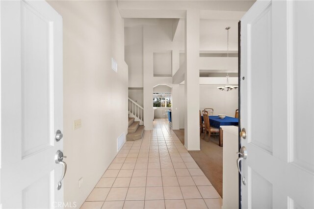 tiled entryway with an inviting chandelier and a towering ceiling