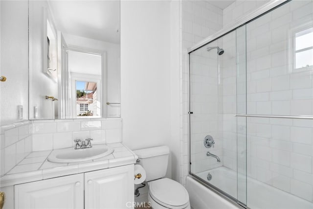 full bathroom featuring shower / bath combination with glass door, vanity, toilet, and tasteful backsplash