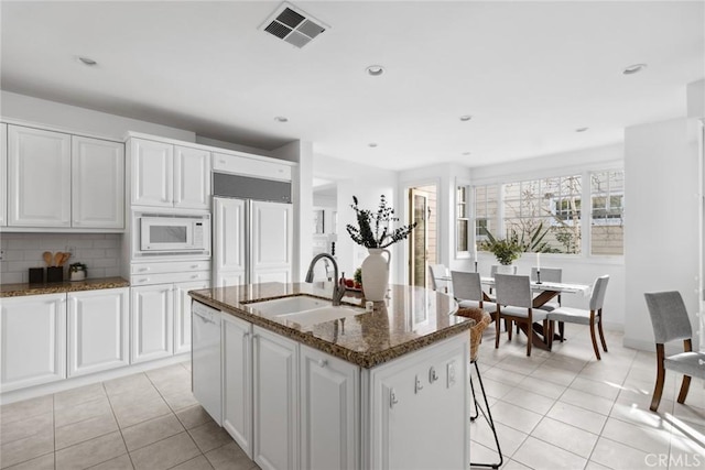 kitchen with white cabinetry, sink, a kitchen island with sink, and built in appliances