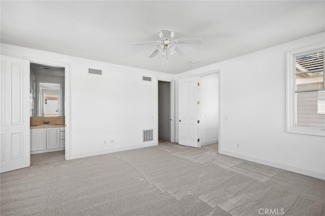 unfurnished bedroom with sink, ensuite bath, light colored carpet, and ceiling fan