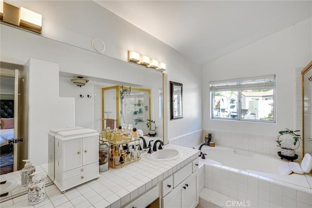 bathroom featuring lofted ceiling, tiled bath, and vanity