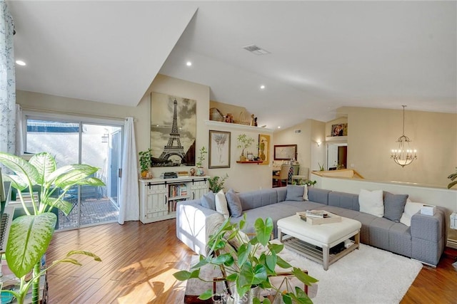 living room with hardwood / wood-style flooring, vaulted ceiling, and a notable chandelier