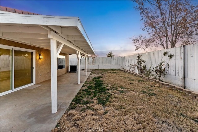 yard at dusk with cooling unit and a patio area