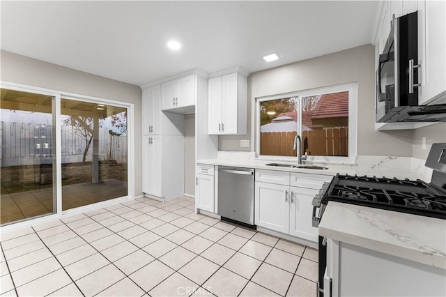 kitchen with white cabinetry, appliances with stainless steel finishes, light stone counters, and sink