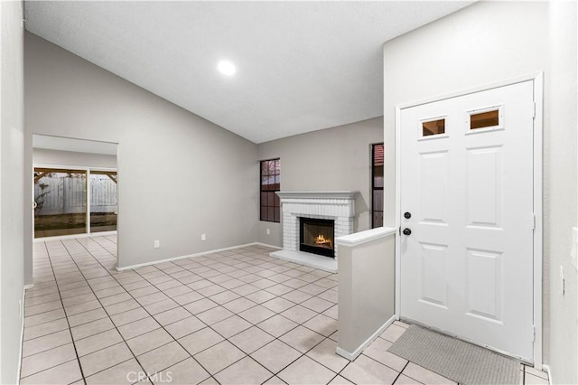 unfurnished living room featuring light tile patterned floors, vaulted ceiling, and a fireplace