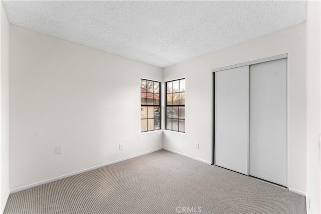 unfurnished bedroom featuring light colored carpet, a closet, and a textured ceiling