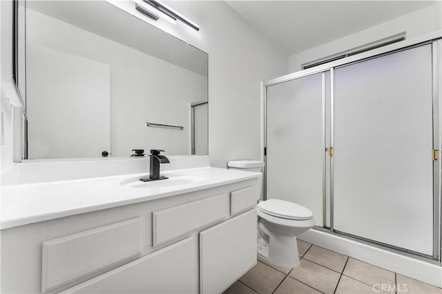 bathroom with walk in shower, vanity, tile patterned flooring, and toilet