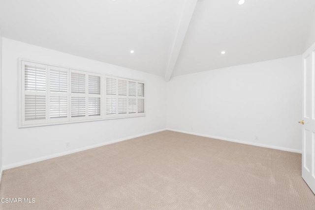 empty room with light colored carpet and vaulted ceiling with beams