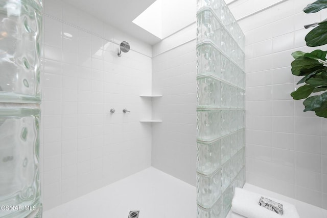 bathroom featuring a skylight and a tile shower