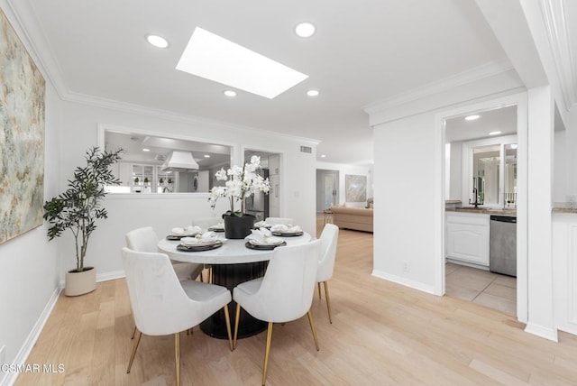 dining area featuring a skylight, light hardwood / wood-style flooring, and crown molding