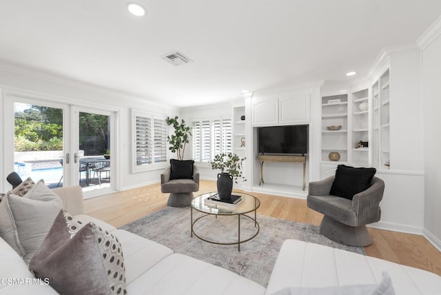 living room featuring built in features, french doors, a wealth of natural light, and crown molding