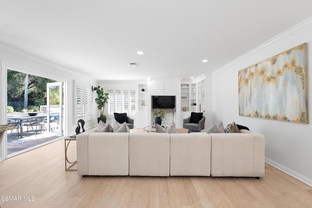 living room featuring light hardwood / wood-style floors, built in shelves, and ornamental molding