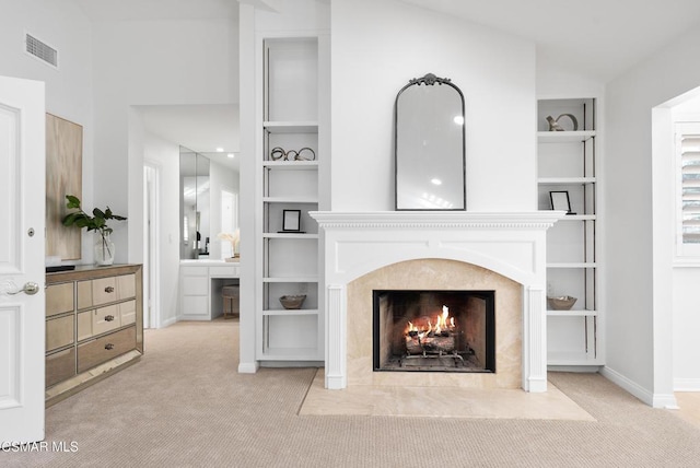 carpeted living room featuring built in features and a premium fireplace