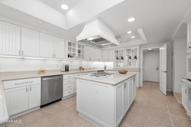 kitchen with dishwasher, white cabinetry, a raised ceiling, and custom range hood