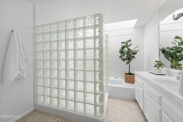 bathroom with a tub to relax in, a skylight, and vanity