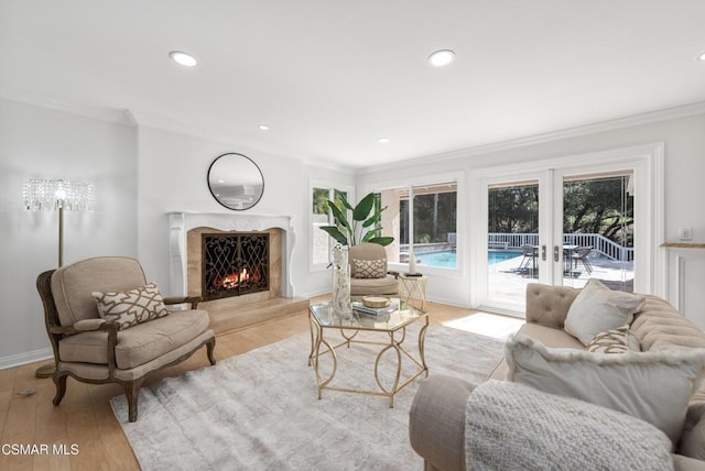 living room with a premium fireplace, french doors, light hardwood / wood-style flooring, and ornamental molding