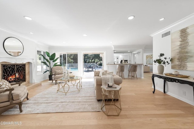 living room with a premium fireplace, light hardwood / wood-style flooring, and crown molding