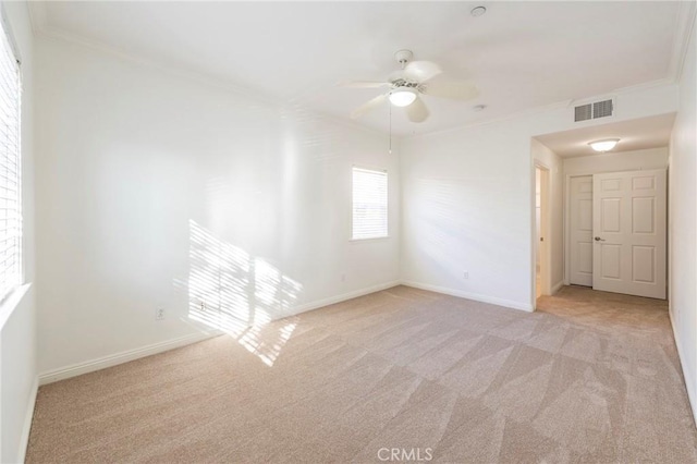 spare room with ceiling fan, light colored carpet, and ornamental molding