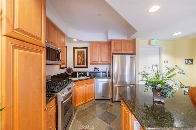 kitchen with appliances with stainless steel finishes, sink, and dark stone countertops