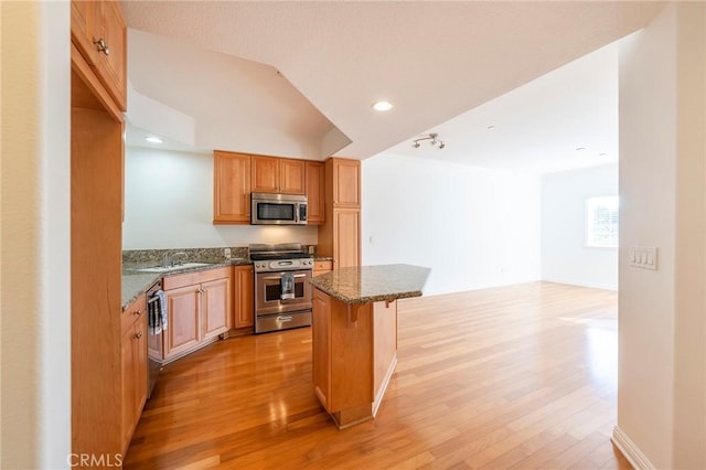 kitchen with lofted ceiling, a kitchen bar, a center island, stainless steel appliances, and light hardwood / wood-style floors